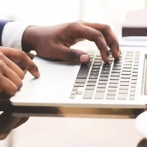 Close-up photo of African-American man's hands on laptop keyboard.