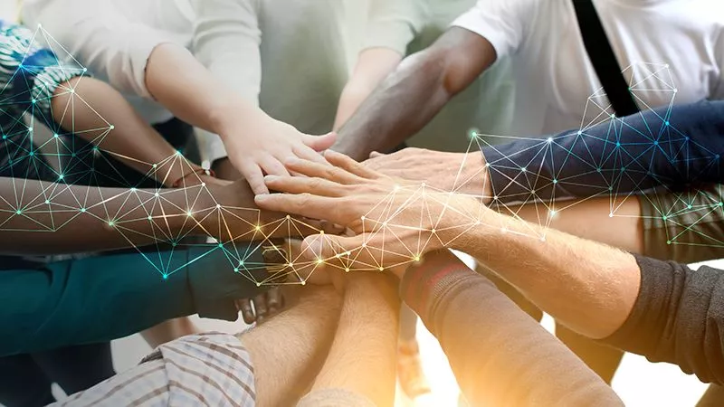 Photo of circle of people's hands of multiple races meeting in middle.